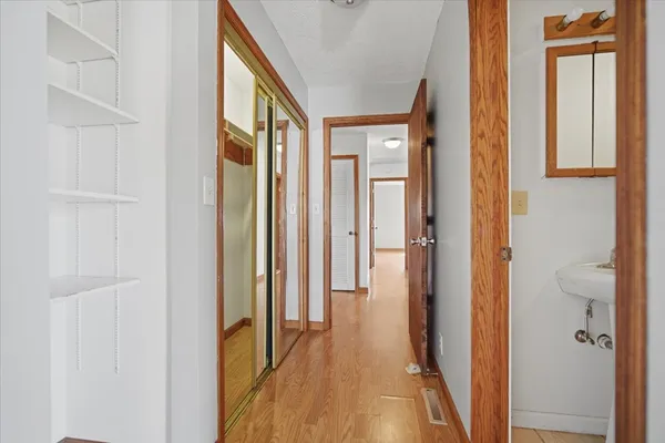 an empty room with wooden floor chandelier fan and windows