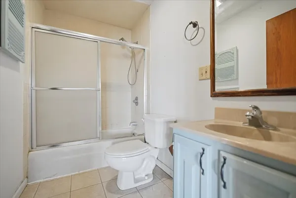 an empty room with a chandelier fan and windows