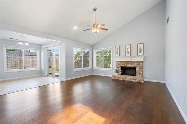 a view of an empty room with wooden floor fireplace and a window
