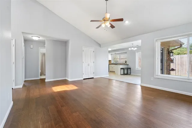 a view of an empty room with window and wooden floor