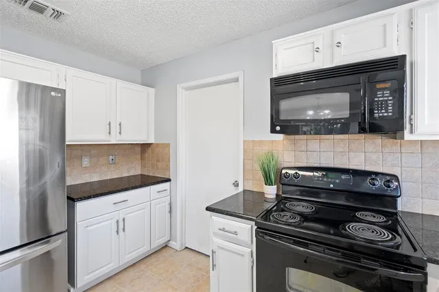 a kitchen with white cabinets and black appliances