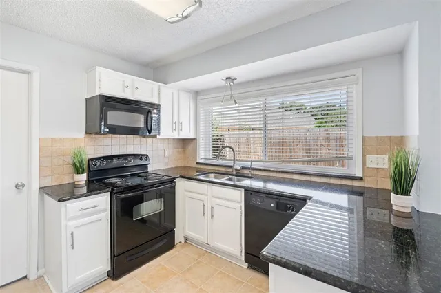 a kitchen with granite countertop wooden cabinets stove top oven and sink