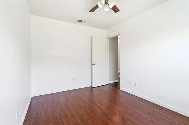 an empty room with a hardwood and ceiling fan