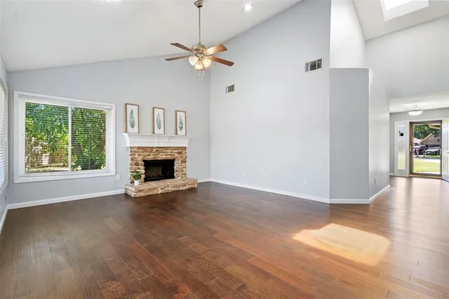 an empty room with wooden floor fireplace and windows