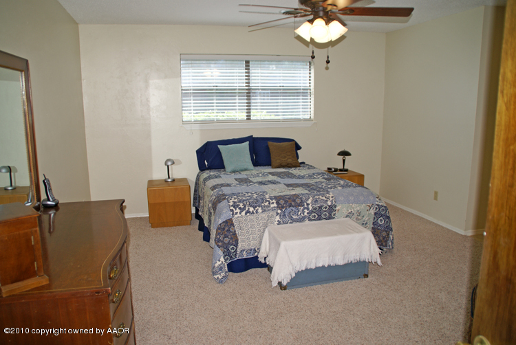 8302 Ranier Drive Amarillo, TX 79110 - Photo 15 of 32 a bedroom with a bed and a chandelier