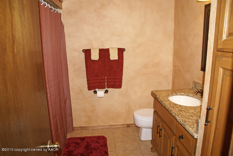 8302 Ranier Drive Amarillo, TX 79110 - Photo 26 of 32 a bathroom with a granite countertop sink a toilet and a mirror