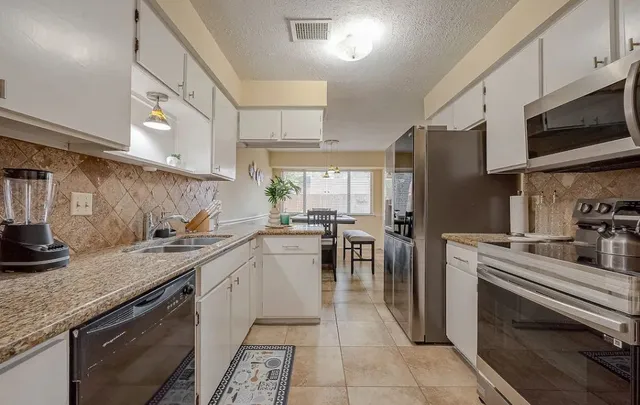 a kitchen with stainless steel appliances granite countertop a refrigerator and a sink