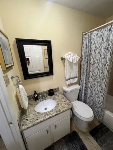 a bathroom with a granite countertop toilet and a sink
