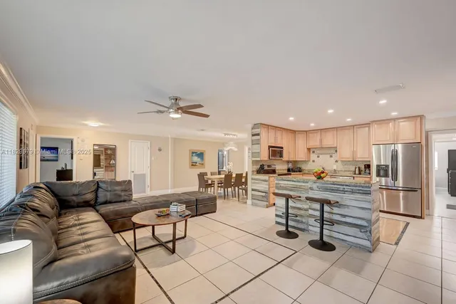 a living room with furniture a kitchen view and a refrigerator