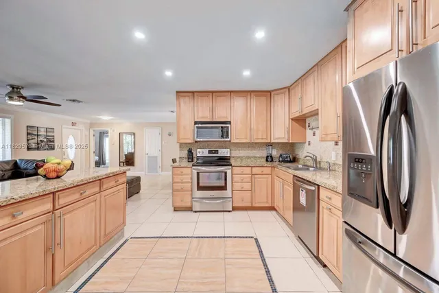 a kitchen with stainless steel appliances granite countertop a refrigerator and a stove top oven