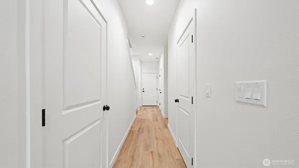 a view of a hallway with wooden floor and a bathroom