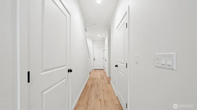 a view of a hallway with wooden floor and a bathroom