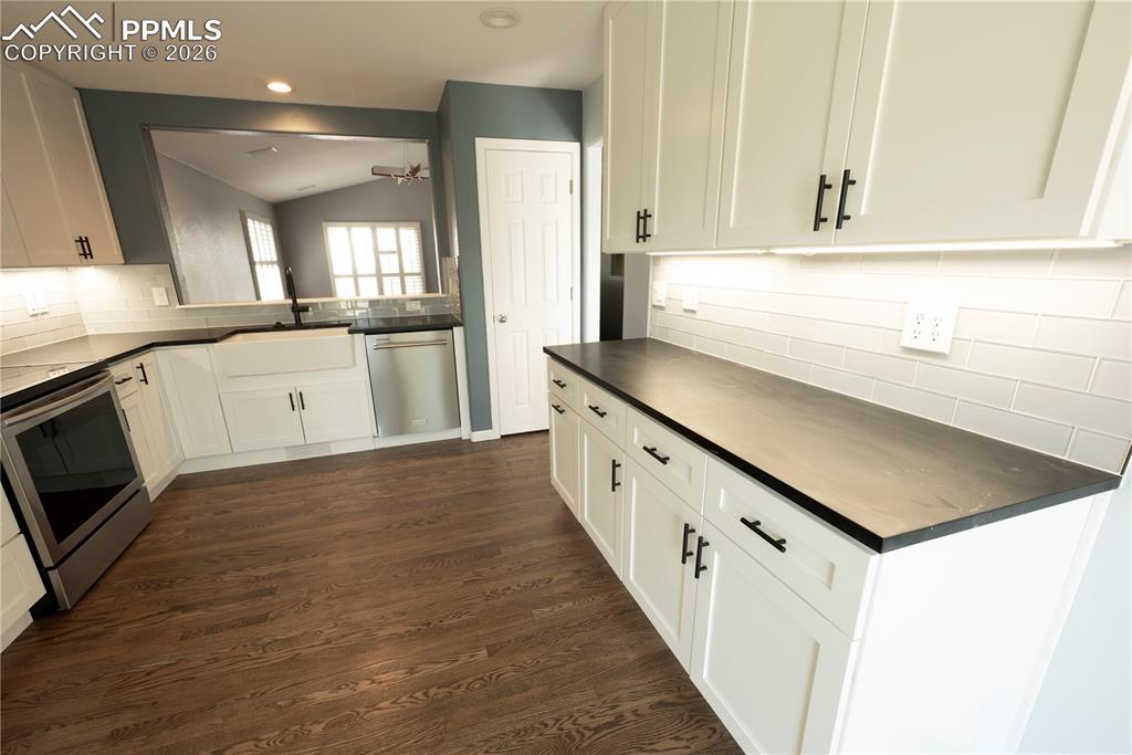 9212 Oakmont Road Peyton, CO 80831 - Photo 3 of 23 a kitchen with granite countertop a sink dishwasher a stove and a refrigerator with wooden floor