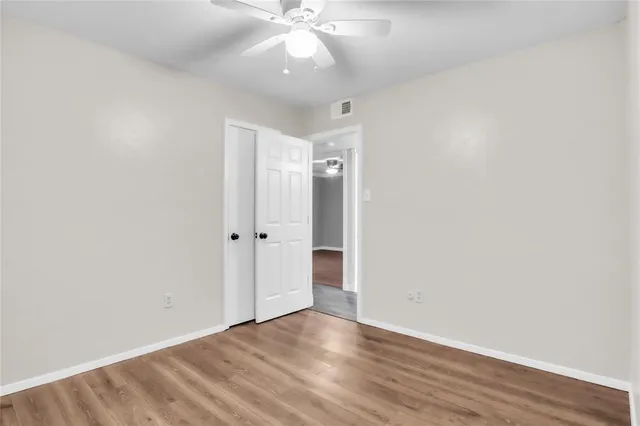 an empty room with wooden floor and fan