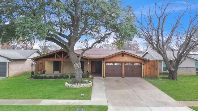 a front view of a house with garden and trees