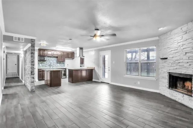 a open kitchen with granite countertop a stove top oven a chimney cabinets and wooden floor