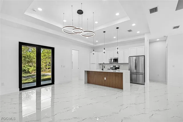 a large kitchen with stainless steel appliances kitchen island granite countertop a refrigerator and a sink