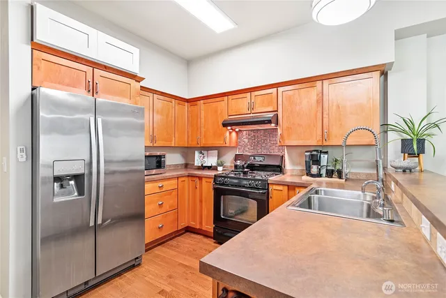 a kitchen with stainless steel appliances granite countertop a refrigerator a stove a sink and a refrigerator