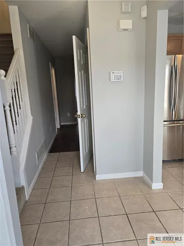 a view of a refrigerator in kitchen and an empty room in wooden floor
