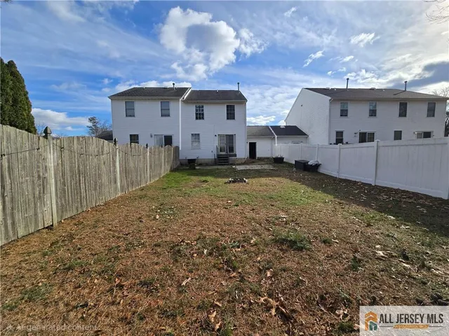 a view of a house with backyard and wooden fence