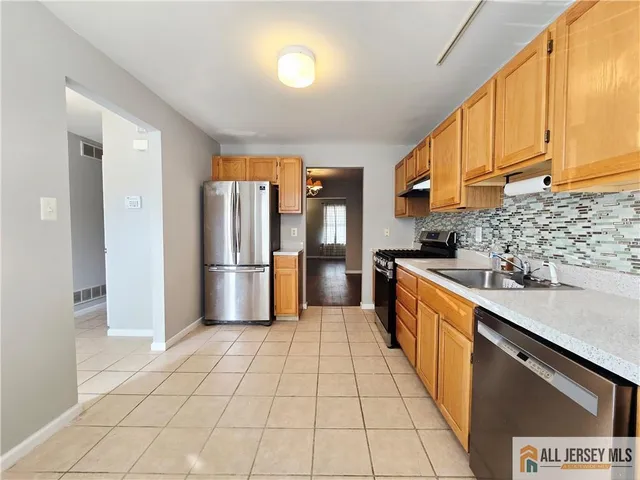 a large kitchen with stainless steel appliances granite countertop a refrigerator and a stove top oven
