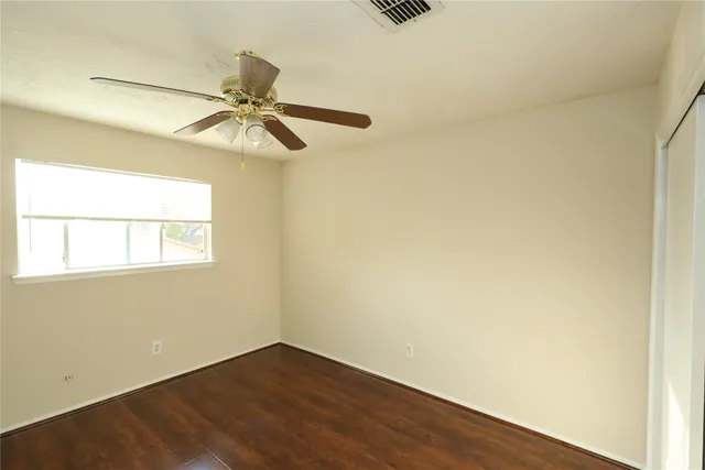 an empty room with a window and a fan