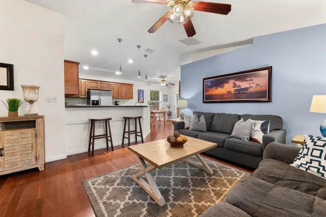 a living room with furniture kitchen view and a wooden floor