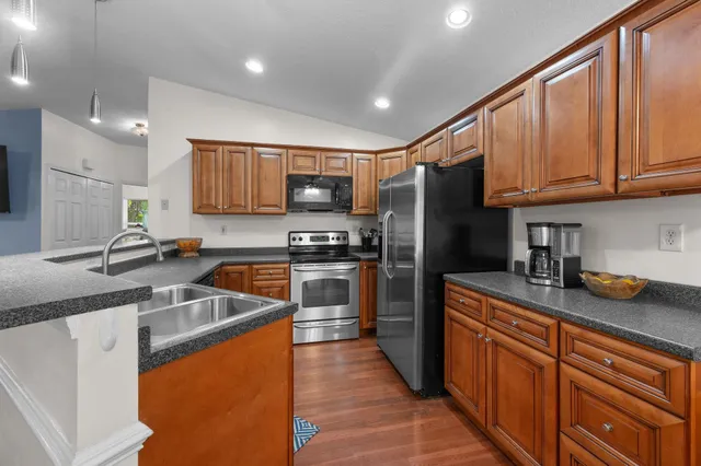 a kitchen with granite countertop stainless steel appliances a refrigerator a stove a sink a counter space and cabinets