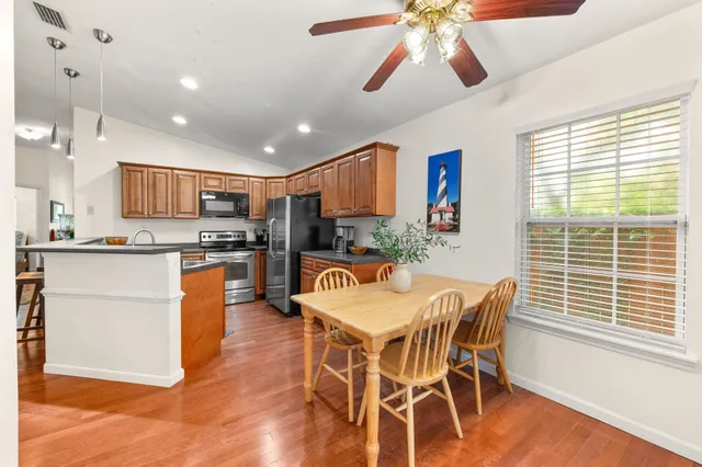 a kitchen with stainless steel appliances kitchen island granite countertop a table chairs and a refrigerator