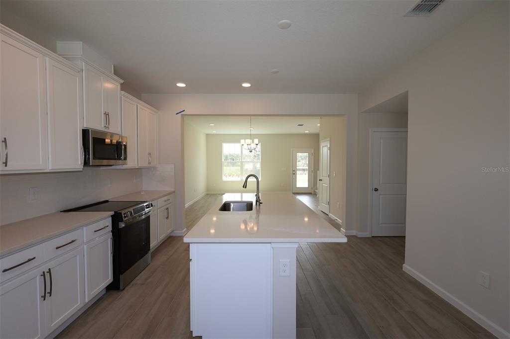 5204 Ctr Lk Rnch Boulevard St. Cloud, FL 34771 - Photo 3 of 24 a kitchen with kitchen island granite countertop a sink dishwasher stove and white cabinets with wooden floor