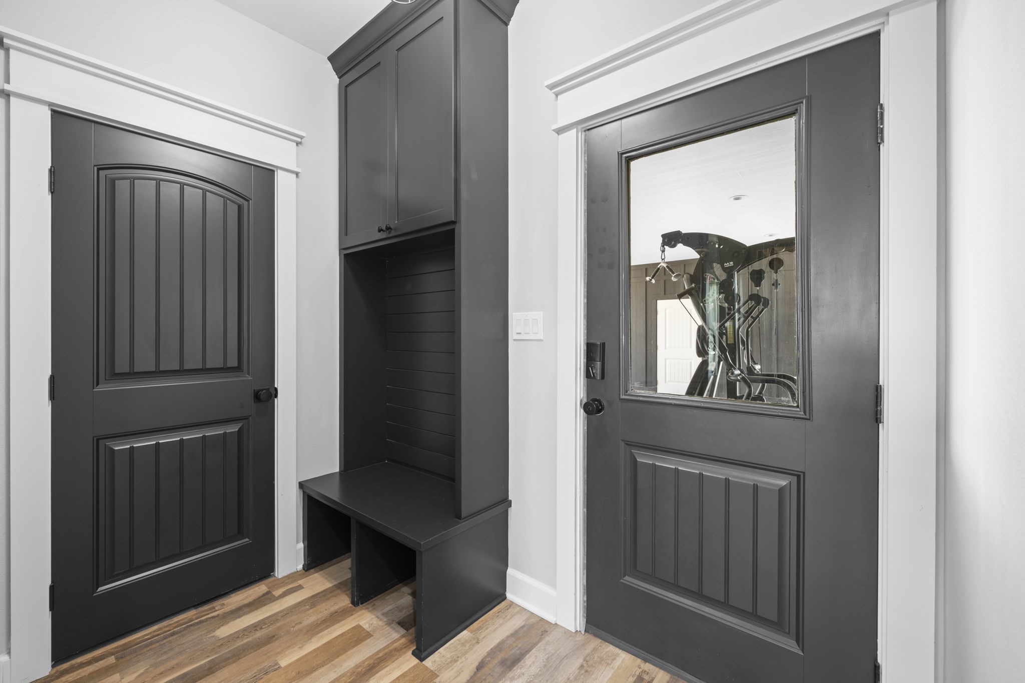 1655 Old Cuero Road Yoakum, TX 77995 - Photo 7 of 24 This functional mudroom combines style and organization with custom built-in storage designed for everyday convenience. Featuring rich wood-look flooring, elegant black paneled doors with crisp white trim, and a built-in hall tree with upper cabinetry, bench seating, and open storage, this space offers the perfect drop zone for shoes, bags, and coats.