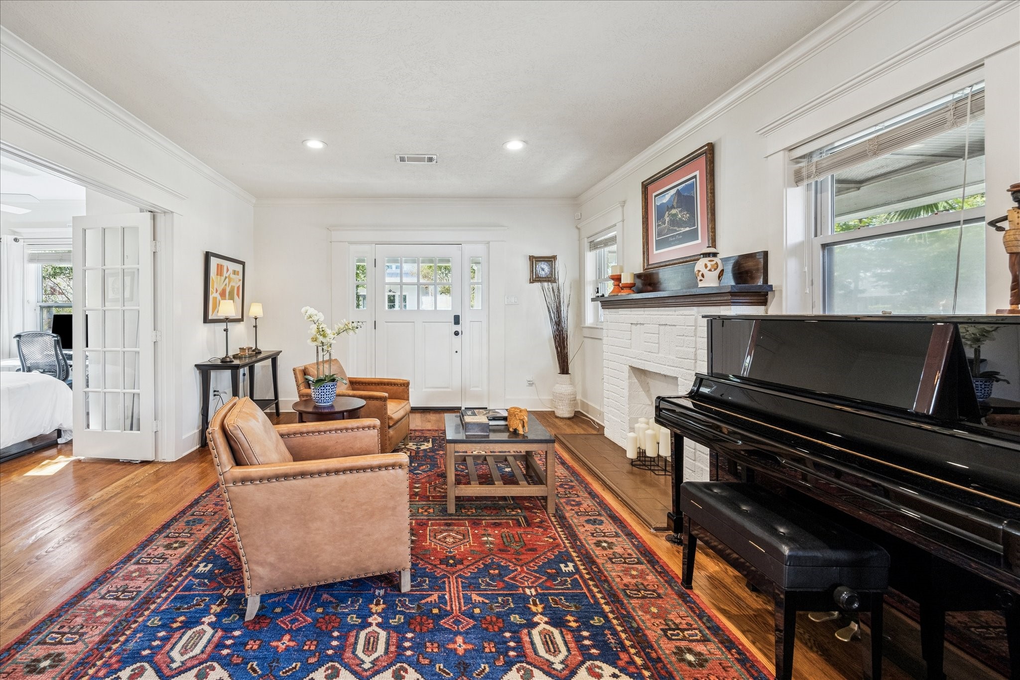 825 Merrill Street Houston, TX 77009 - Photo 17 of 37 Step into this inviting living room, featuring crown molding, hardwood floors, neutral paint, a fireplace and recessed lighting. Large windows and a glass-paned front door fill the space with natural light.