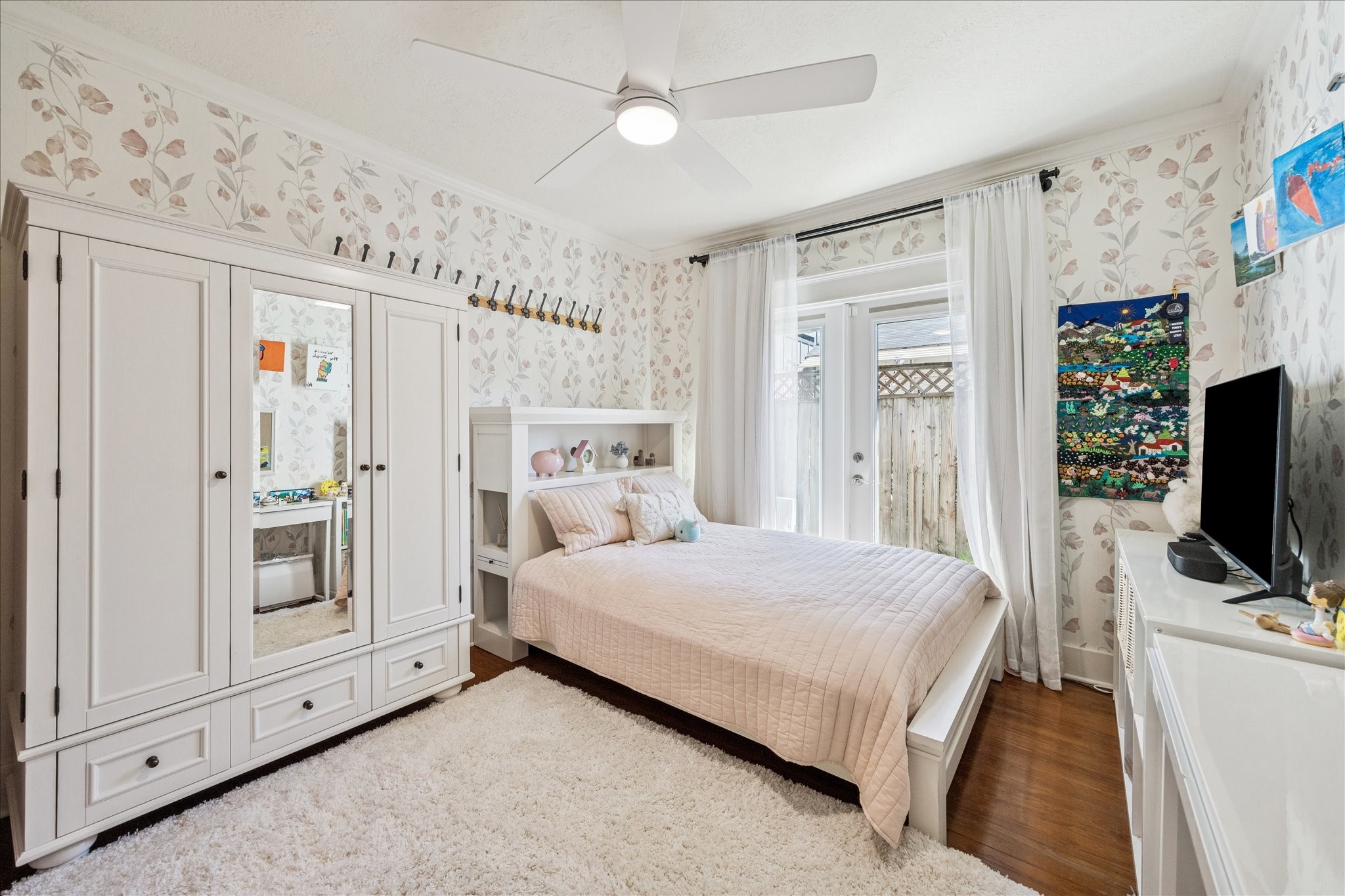 825 Merrill Street Houston, TX 77009 - Photo 24 of 37 Second bedroom featuring hardwood floors, charming wallpaper, a ceiling fan, and French doors that fill the space with natural light.