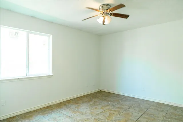 a view of an empty room with window and chandelier fan
