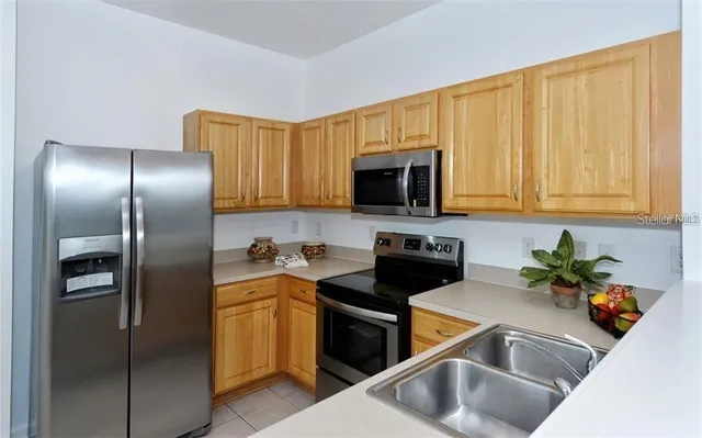 a kitchen with stainless steel appliances granite countertop a refrigerator a sink a stove with cabinets and a refrigerator