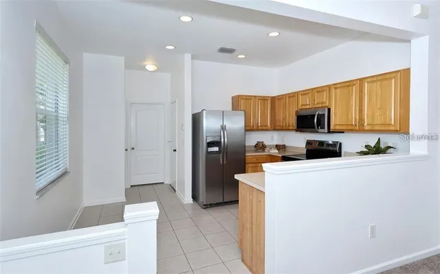 a kitchen with stainless steel appliances granite countertop a refrigerator a stove a microwave oven a sink dishwasher and white cabinets with wooden floor