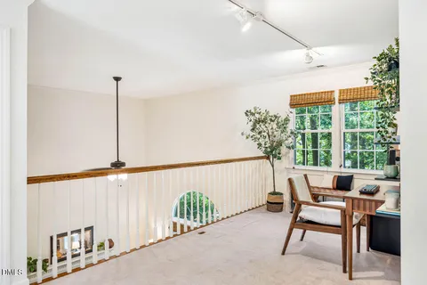 a bedroom with a bed a standing fan and a window