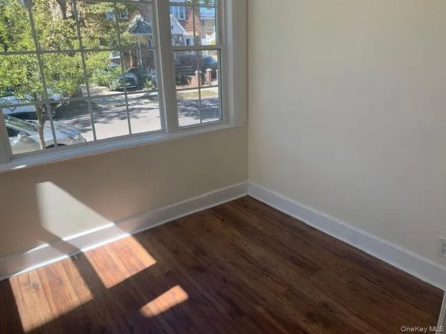 a view of an empty room with wooden floor and windows
