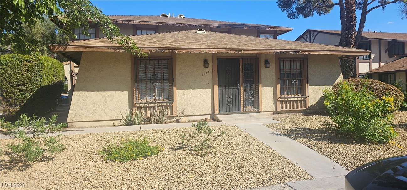 1344 Lorilyn Avenue, Unit 2 Las Vegas, NV 89119 - Photo 1 of 15 Bungalow-style home featuring stucco siding, a porch, and a shingled roof