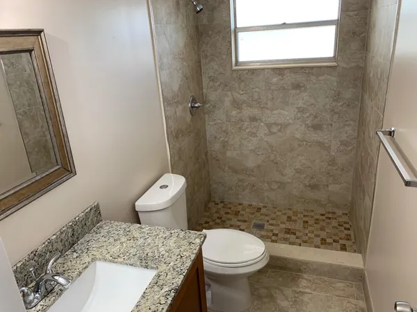 a bathroom with a granite countertop toilet a sink and a mirror