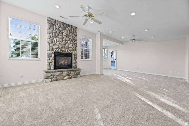 4117 North Wolf Ridge Circle Eden, UT 84310 - Photo 28 of 63 Spacious living area featuring a floor-to-ceiling stone fireplace, plush carpeting, recessed lighting, and multiple windows with blinds