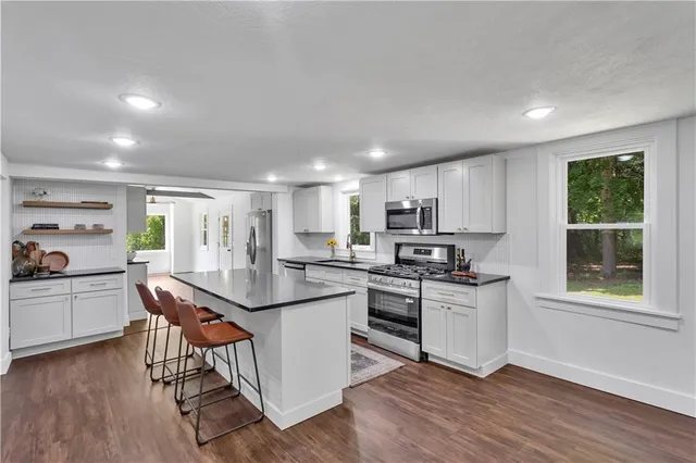 a kitchen with white cabinets appliances and wooden floor