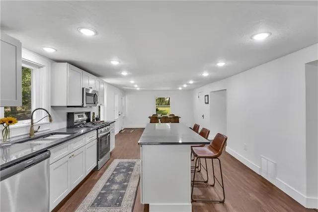 a kitchen with stainless steel appliances granite countertop a sink a stove top oven a counter space and cabinets