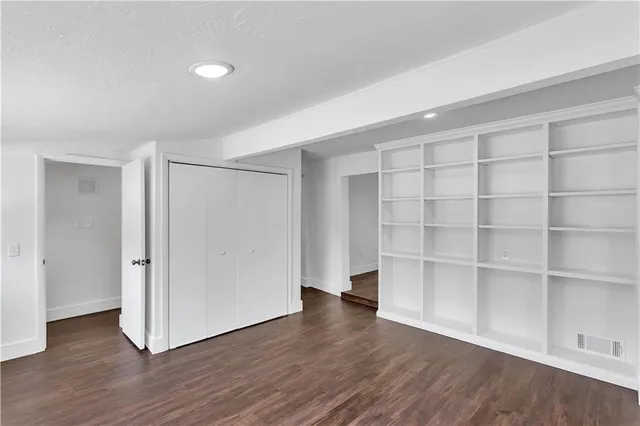 a view of an empty room with wooden floor and closet