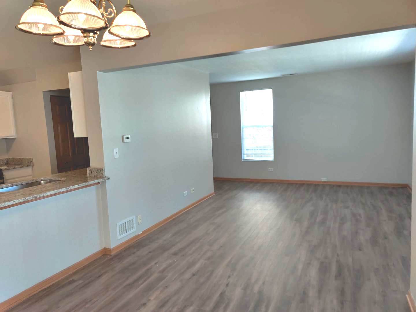 889 Symphony Drive Aurora, IL 60504 - Photo 13 of 24 a view of a room with wooden floor and chandelier