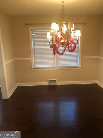 a view of a room with wooden floor chandelier and windows