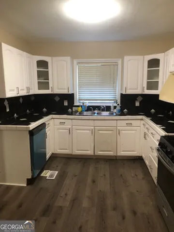 a kitchen with a sink white cabinets and white appliances