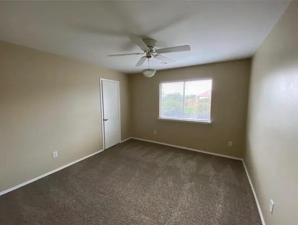 an empty room with windows and ceiling fan