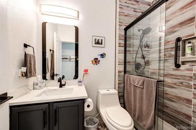 a bathroom with a sink a toilet a mirror and shower