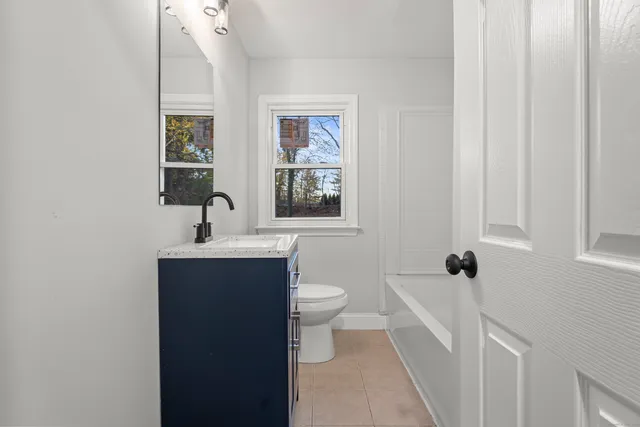 a bathroom with a toilet a sink a mirror and a window